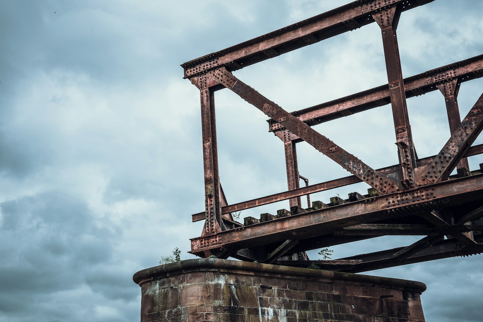 an old rusted metal structure on top of a brick wall Photo by Timon Reinhard